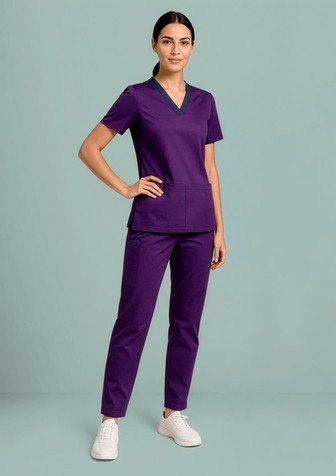 A model wearing purple women's Riley straight leg scrub pants paired with a matching top, set against a light background.