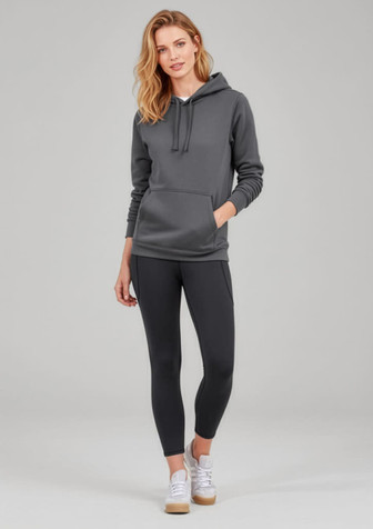 A woman in a grey hoodie poses with black 7/8 length leggings. The outfit includes casual white sneakers.