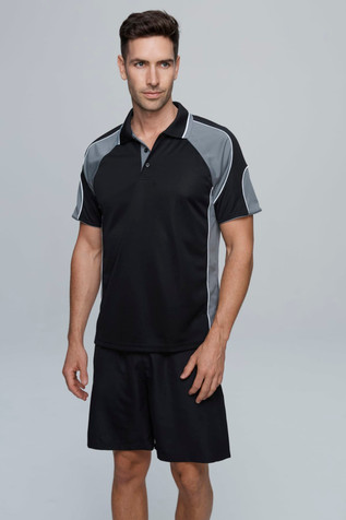 A model wearing a black and grey polo shirt and black shorts, featuring a logo on the shirt.