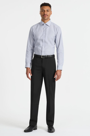 A man wears a light blue long sleeve button-up shirt paired with black trousers and shoes. The shirt features a logo.