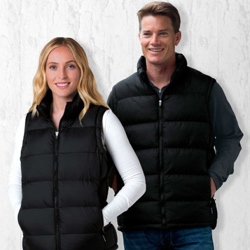 Two individuals wearing black puffa vests, standing against a textured white background. The vests have front zip closures and pockets.