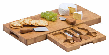 A bamboo cheese board set featuring assorted cheeses, crackers, grapes, and stainless steel knives with wooden handles.