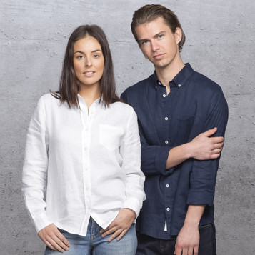 A white linen button-up shirt worn by a woman and a navy button-up shirt worn by a man, both against a textured background.