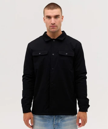 A black soft shell jacket with two chest pockets and buttons, worn by a model against a neutral background.
