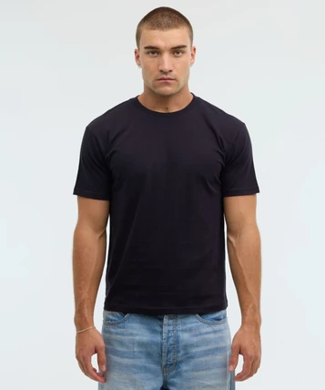 A dark navy essential tee displayed on a male model, paired with light blue denim jeans, featuring a simple design.
