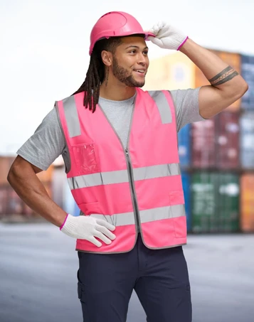 A pink high-visibility safety zip vest with reflective stripes, worn by a person in a grey shirt and pink helmet.