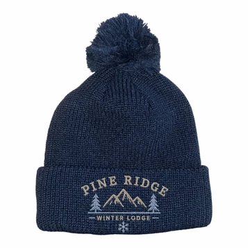 A navy knitted beanie with a pom pom on top and a logo featuring mountains and text.