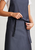 A navy blue Urban Bib Apron featuring a front pocket and adjustable tie at the waist, with branding visible.