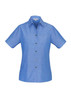 A blue chambray short sleeve button-up shirt with a front pocket and button detailing. It has a logo on the label.