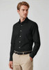 A black long sleeve button-up shirt worn by a model, featuring a sleek design and a collar, paired with beige trousers.
