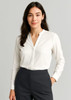 A white long sleeve blouse with a v-neckline and button-up design, paired with dark grey trousers.