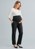 A pregnant woman in a white top and black maternity pants, with pockets and a stretchy waistband, stands confidently.