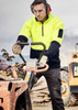 A man wears a high visibility yellow and navy unisex 1/2 zip pullover while operating machinery on a work site.