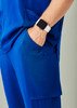 Blue straight leg scrub pant featuring pockets, worn with a watch on the wrist.
