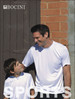 A white sublimation T-shirt, designed for kids, worn by a boy and a man, both smiling against a brick wall.