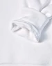 A close-up of a white fleecy hoodie sleeve featuring a soft, textured cuff. It has a logo on the fabric.