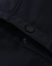 A close-up of a navy softshell jacket featuring a snap button and interior stitching details.
