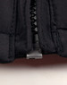 A close-up of a black heavy quilted jacket, highlighting the zip and stitching details. The jacket features a logo.