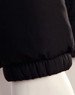 A black heavy quilted puffer jacket featuring a gathered cuff design, displayed on a mannequin.