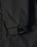 A close-up of a black long line stadium jacket featuring adjustable wrist cuffs and a logo.