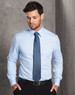 A light blue long-sleeve button-up shirt worn by a man, featuring a pocket and with a tie.