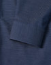 A close-up of a navy men's button-up shirt featuring a pin dot pattern and a cuff detail.