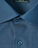 A close-up of a blue pin dot stretch button-up shirt featuring a patterned fabric and a branded tag.