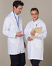 A unisex long sleeve white lab coat worn by two people, each with a notepad and clipboard.