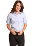 A short-sleeved blue women's fine twill button-up shirt worn by a smiling model. The shirt features a collar and buttons.