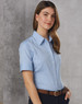 A blue women's short sleeve button-up shirt with a collar, featuring a logo on the chest and a belt.
