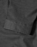 A close-up of a black pin dot stretch fabric with a 3/4 sleeve cuff of a button-up shirt. The shirt features a logo.