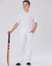 A boy stands proudly in a white cricket polo shirt and matching trousers, holding a cricket bat. The outfit features a logo.