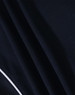 A close-up of a navy blue polo shirt fabric with a textured pattern and a white trim detail.