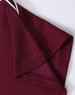 A close-up of a maroon kids' polo shirt showing the collar and sleeve details. The shirt features a subtle texture and has a logo.
