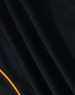 A close-up of a black polo shirt featuring a yellow accent and textured fabric with a logo.