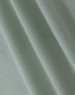 A close-up of light green cotton fabric with a smooth texture, showcasing fine weaves and folds.