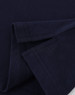 A close-up of a navy blue cotton stretch polo shirt, showcasing the fabric and folded sleeves. It features a logo.