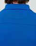 A close-up view of the back of a men's polo shirt in vibrant blue, featuring a collar and a branding label.