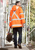 A waterproof orange jacket with reflective strips, worn by a man carrying a tool bag, against a construction backdrop.