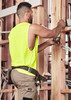 A sleeveless high-visibility yellow tee worn by a man working on a construction site, measuring with a tool.