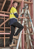 A man in a blue and yellow long sleeve shirt climbs a ladder in an under-construction area. The shirt features reflective segments.