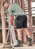 Men's streetwear comfort shorts in black, paired with a green shirt, worn by a man working on a construction site.