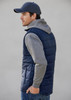 A navy men's alpine vest with grey hooded sleeves, featured on a model facing sideways. The vest has a logo.