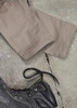 A pair of beige cargo pants laid out flat next to a black boot on a textured surface.