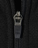 A close-up of a black zip on a fleece jacket featuring a YKK zipper. The fabric appears textured and soft.