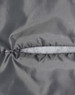 A close-up of a grey quilted fabric with a zip closure, highlighting the texture and stitching details.