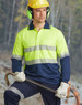 A bright yellow and navy long-sleeve safety polo shirt with reflective stripes, worn by a worker in safety gear.