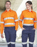 Hi Vis long-sleeve shirt in orange with reflective tape, worn by two models standing outdoors in navy pants.