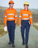 Two individuals wear unisex cotton stretch ripstop work pants in navy, paired with bright orange shirts and hard hats.