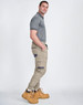 Unisex cotton stretch drill cuffed work pants in khaki with side pockets, paired with a grey polo and yellow work boots.